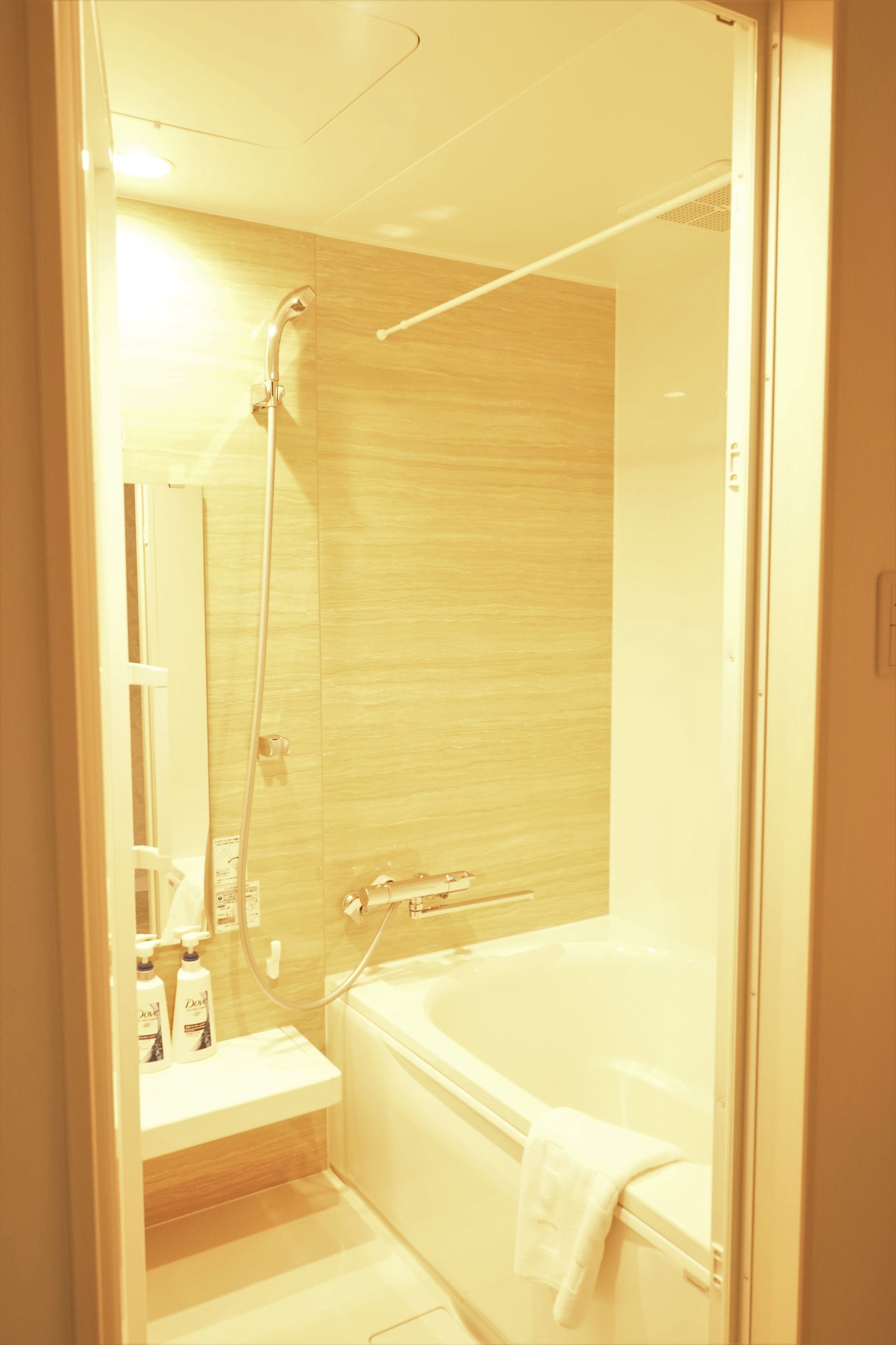 Ein modernes Badezimmer mit einer gläsernen Duschkabine, einer weißen Badewanne und einem kleinen Waschtisch mit Pflegeprodukten.
