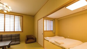 Una habitación japonesa tradicional con suelo de tatami, una mesa baja, un sofá y una cama con ropa blanca.