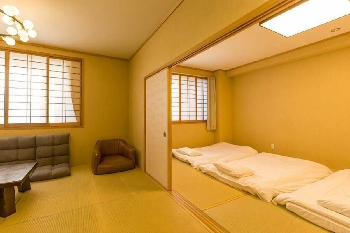A traditional Japanese room with tatami flooring, a futon bed, a low table, and a sliding door.