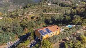 A yellow building with solar panels, surrounded by a mountainous landscape and a swimming pool. - La Casa al Monte by Interhome (Camaiore)