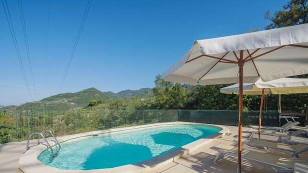 A swimming pool with a view of the mountains, surrounded by lounge chairs and umbrellas. - La Casa al Monte by Interhome (Camaiore)