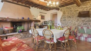 A rustic dining area with a stone wall, wooden beams, and a fireplace. - Vacation home Bruna by Interhome (Massarosa)
