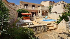 Une villa en pierre dotée d’une piscine, d’un espace salon extérieur et d’un patio couvert.