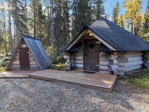 A log cabin with a wooden deck and a metal roof structure.