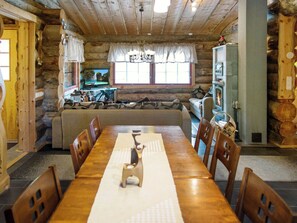 A wooden dining table with chairs, a television on a stand, a sofa, and a fireplace.