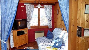 Uma cabana acolhedora com uma cama, uma TV e uma mesinha.