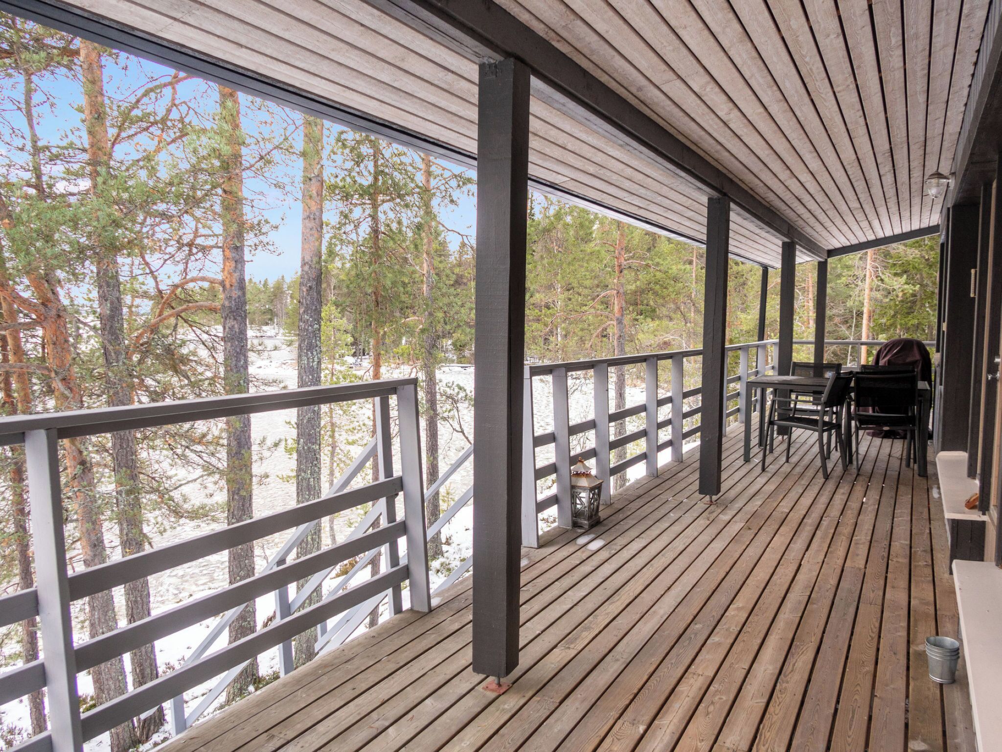 A wooden deck with a railing, a table, and chairs.