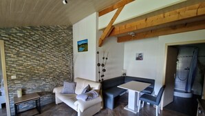 Una sala de estar con pared de piedra, un sofá, una mesa y un rincón con ducha.