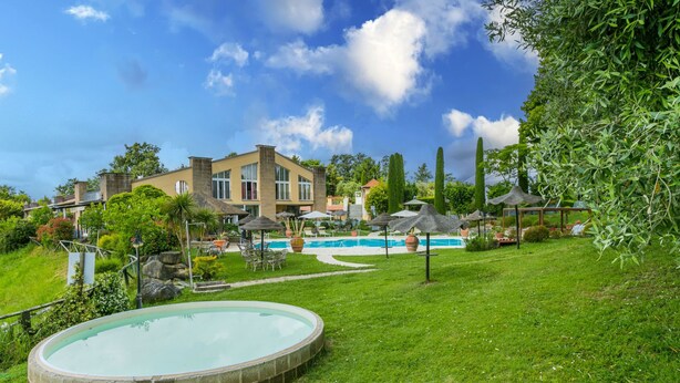 A pool area with a circular pool, lounge chairs, and umbrellas.