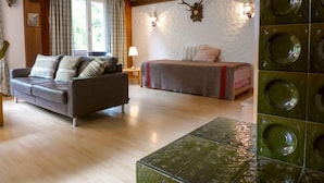 Una habitación acogedora con piso de madera, un sofá, una cama y una pared decorativa con diseños circulares.