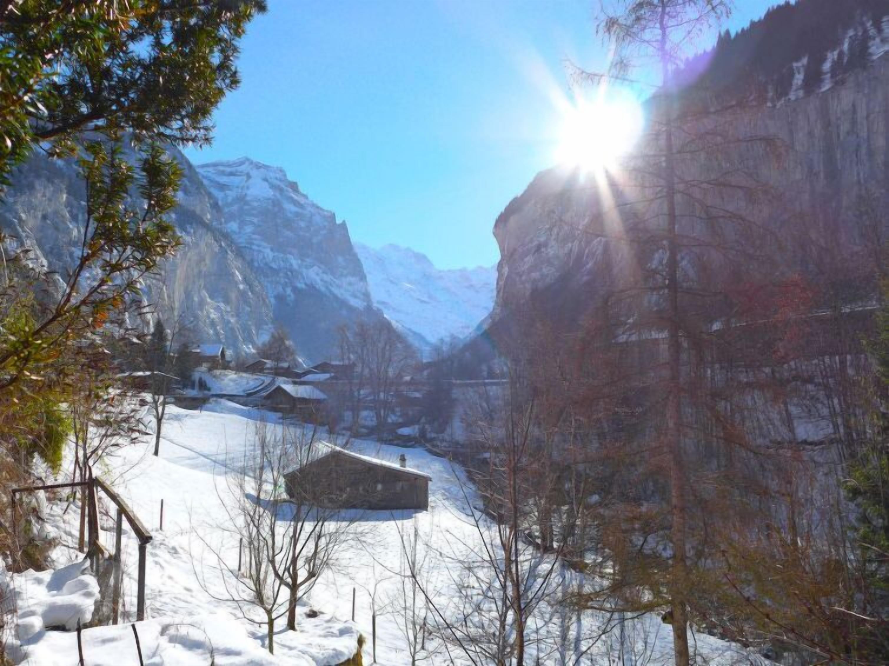 Eine verschneite Berglandschaft mit einer Holzhütte und blauem Himmel.