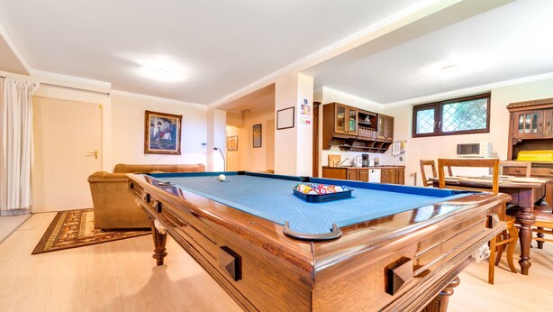 A pool table in a well-lit room with wooden cabinets and a dining area. - Marcyporęba by Interhome (Marcyporeba)