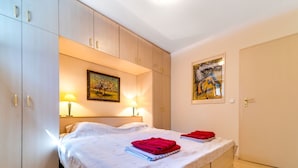 A bedroom with a bed, two lamps, a painting, and a door. - Marcyporęba by Interhome (Marcyporeba)