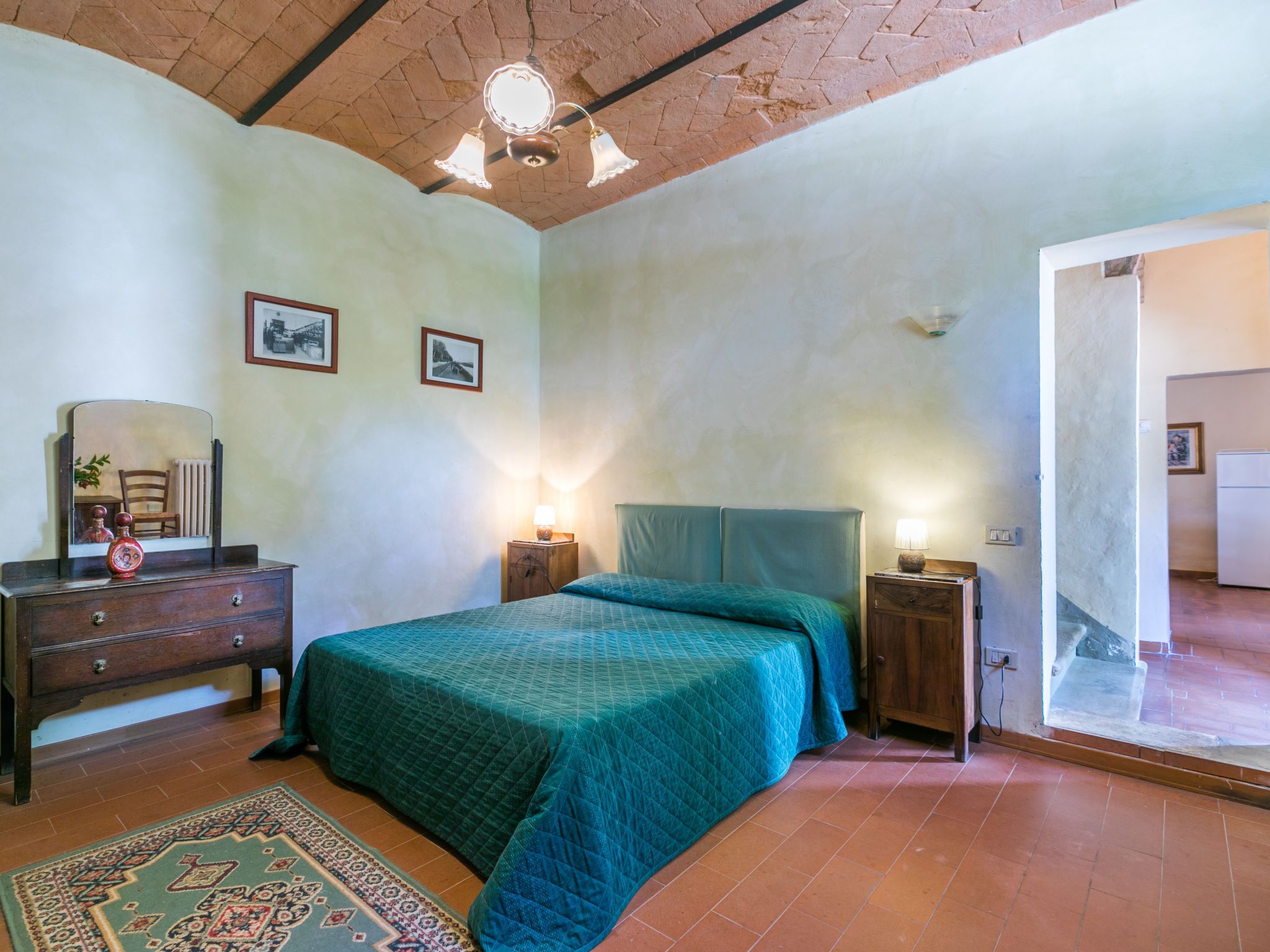 Een slaapkamer met een bed, een dressoir, nachtkastjes en een spiegel.