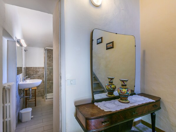 A bathroom with a sink, mirror, and two decorative vases on a wooden dresser.