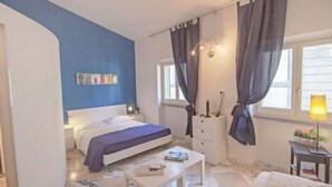 A bedroom with a bed, bedside table, lamp, and curtains. - Bufalini 2 - Raffaello by Interhome (Florence)