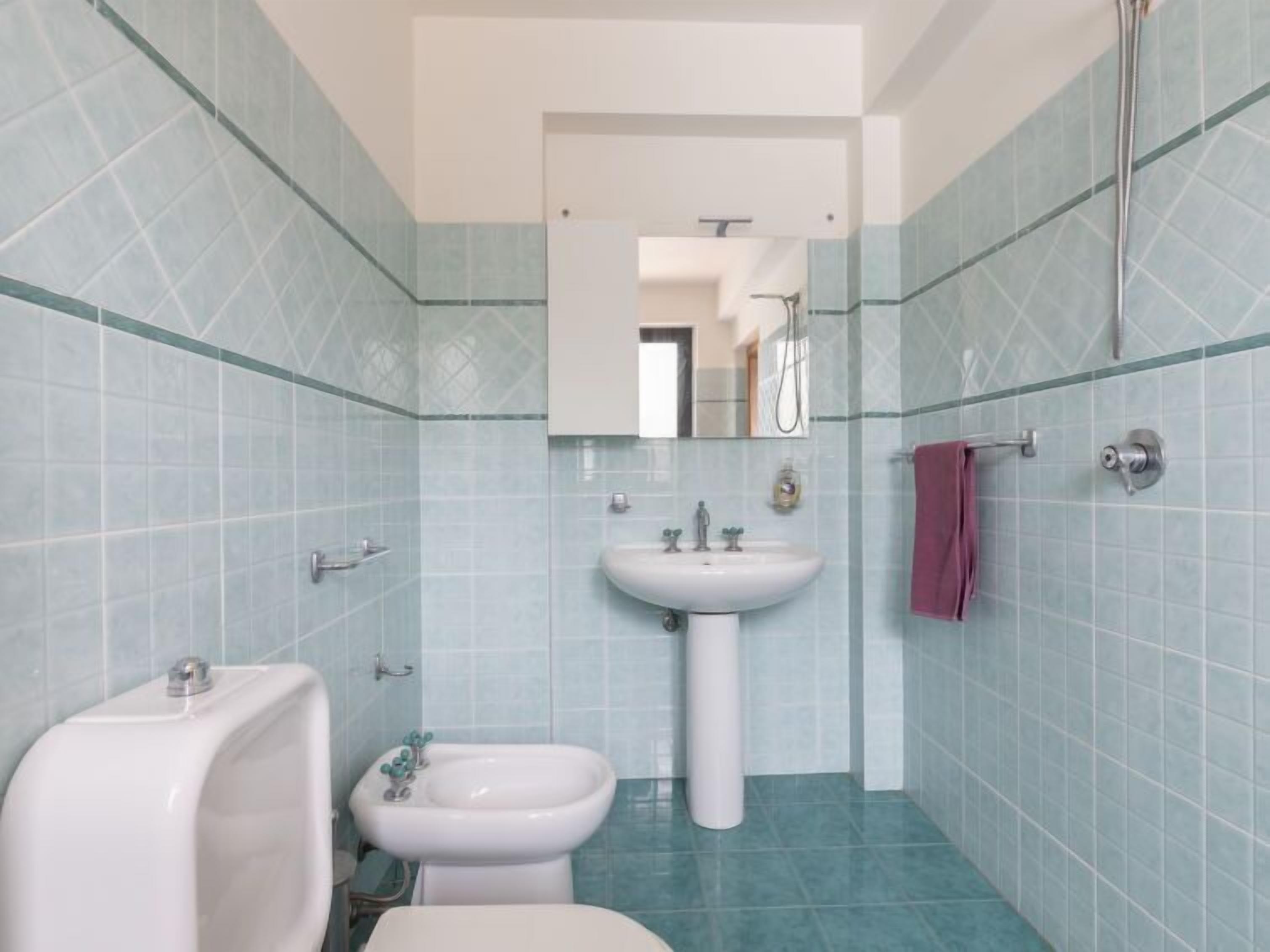 Un baño con lavamanos pedestal, un bidé y un inodoro.