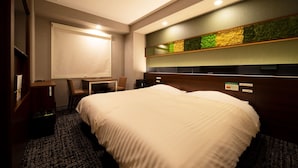A hotel room with a large bed, a desk, and a seating area. - Super Hotel Ehime Ozu Inter (Ozu)