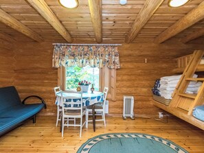 A cozy cabin interior with a dining table, chairs, a sofa, a radiator, and a bunk bed. - Honkalinna by Interhome (Mikkeli)