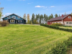 A two-story log cabin with a well-maintained lawn and a red barn in the background. - Honkalinna by Interhome (Mikkeli)