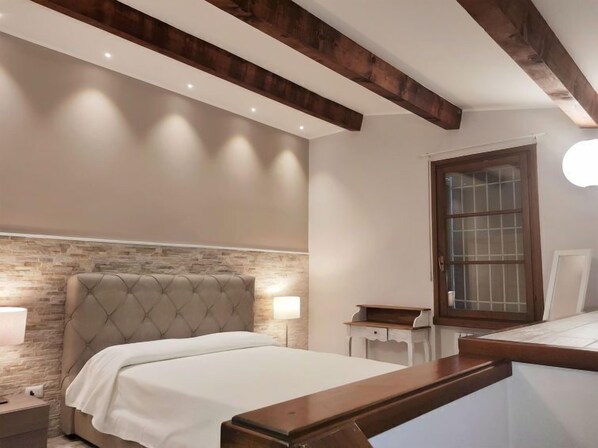 A bedroom with a bed, a nightstand, a bedside table, a lamp, and a wooden headboard.