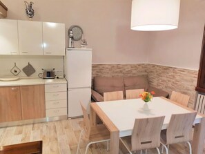 A modern kitchen with white cabinets, a built-in oven, and a dining area with a wooden table and chairs.