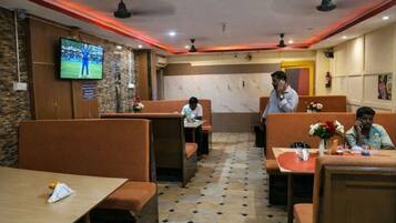 Un restaurante con cabinas y mesas, una pantalla de televisión en la pared y un suelo con diseño.