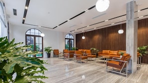 A modern lobby with a mix of seating areas, large windows, and indoor plants. - The Twin Hotel (Bai Chay)