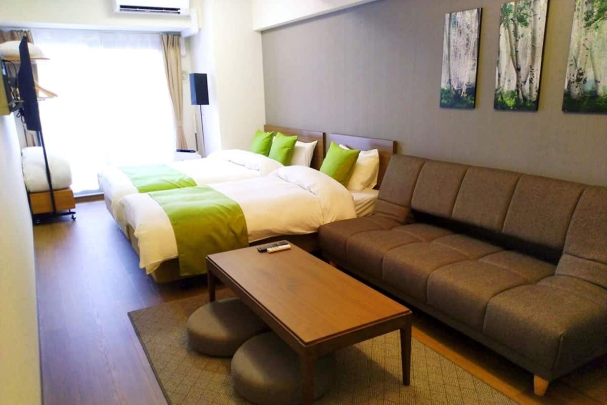 Una habitación de hotel con cama, sofá, una mesita y suelo alfombrado.