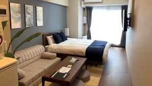 Ett hotellrum med en säng, en soffa, ett skrivbord och en tv.