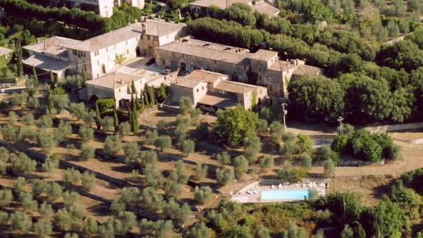 Eine Vogelperspektive auf ein ländliches Dorf mit traditionellen Steinhäusern, einem zentralen Innenhof und einem Schwimmbad.