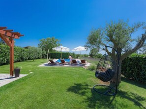 A backyard with a pool, lounge chairs, and umbrellas.