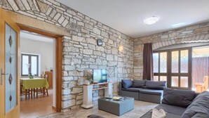 A living room with stone walls, a sofa, a coffee table, and a television. - Vacation home Blog 2 by Interhome (Poreč/Sv. Lovreč)