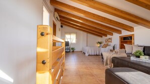 A spacious living area with a high ceiling and exposed wooden beams, a sofa, a coffee table, and a bed with a view to the outside. - Vacation home Sally by Interhome (Deltebre)