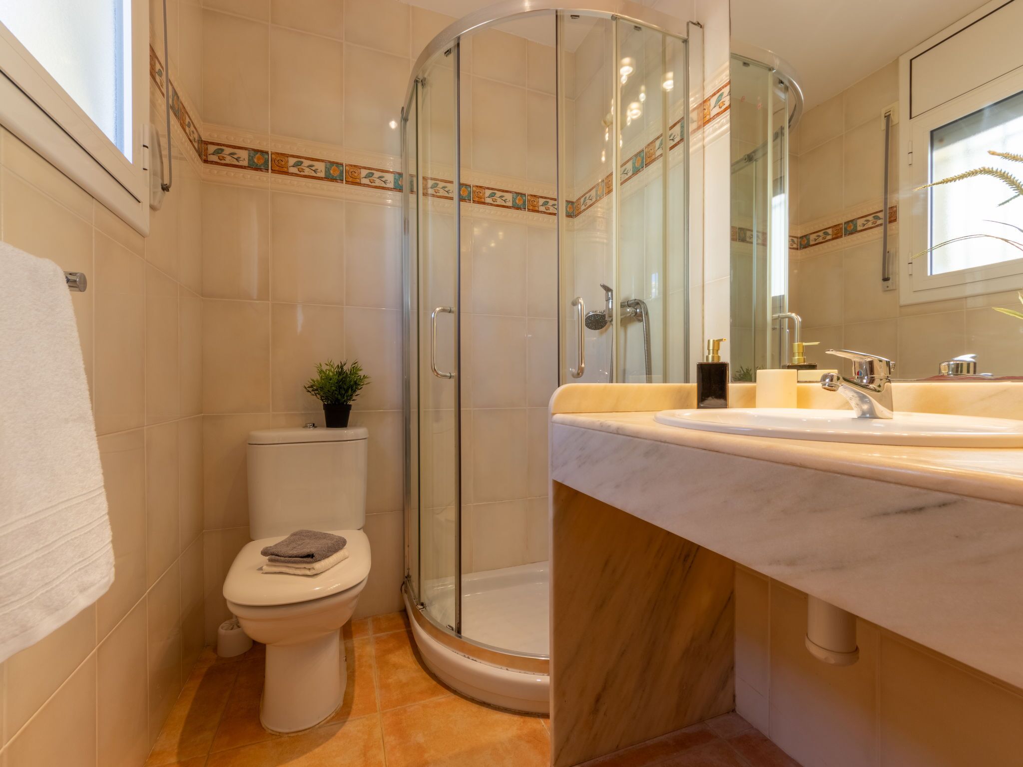 Une salle de bain moderne dotée d’une douche à parois de verre, de toilettes et d’un lavabo avec un plan de travail en marbre.