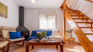 A living room with a sofa, chair, wooden coffee table, and a staircase. - Vacation home Sally by Interhome (Deltebre)