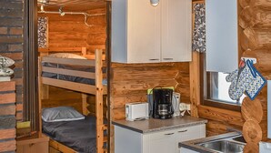 Una habitación tipo cabaña compacta con literas, kitchenette y baño pequeño.