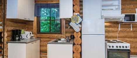 A compact kitchen with white cabinetry, a refrigerator, a stove, and a microwave.