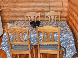 A wooden dining table with a camouflage tablecloth, surrounded by four wooden chairs with cushioned seats.