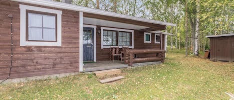 Een houten blokhut met een veranda, schoorsteen en een klein terras.