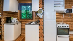 Una cocina compacta con gabinetes blancos, un refrigerador, estufa y microondas.