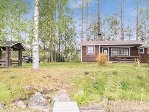 A rustic cabin with a wooden exterior, a porch, and a small garden area with a wooden deck leading to the entrance.
