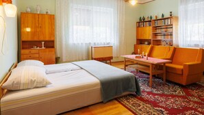 A cozy bedroom with a bed, a wooden wardrobe, a bookshelf, and a sofa. - Vacation home Peach by Interhome (Balatonfenyves)