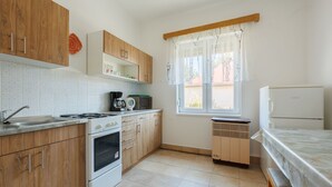 A kitchen with wooden cabinets, a stove, a microwave, and a refrigerator. - Vacation home Peach by Interhome (Balatonfenyves)