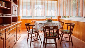 A dining room with a round table, six wooden chairs, and a bookshelf. - Vacation home Peach by Interhome (Balatonfenyves)