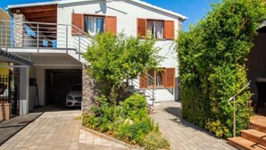 Une maison à deux étages avec un balcon, un garage et un jardin bien entretenu.