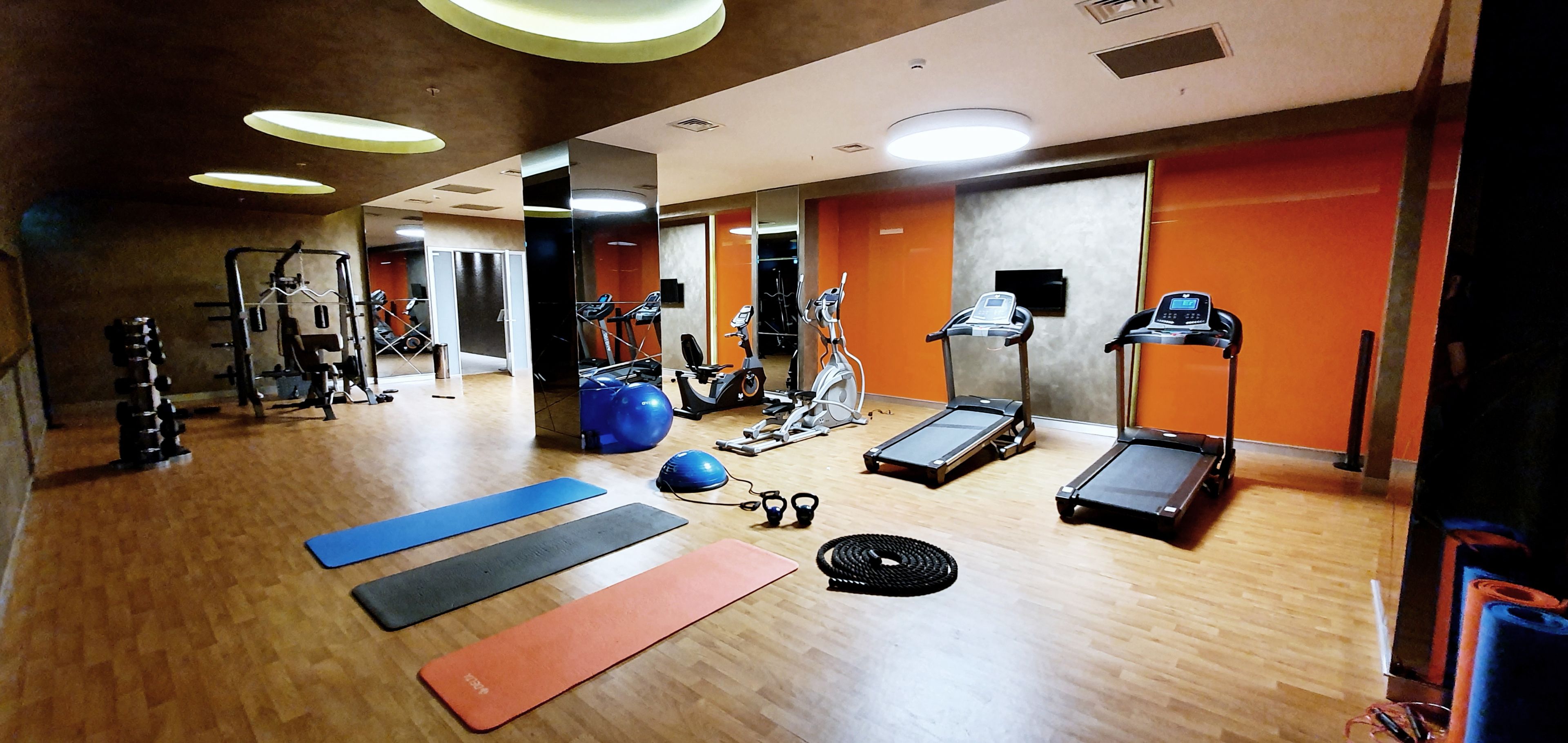 A gym with exercise equipment, mats, and treadmills.