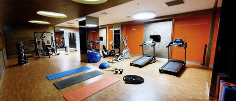 A gym with exercise equipment, mats, and treadmills.