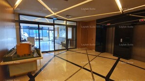 Um saguão com design moderno, com um balcão de recepção, área de estar e um elevador.