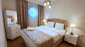 Quarto de hotel bem arrumado, com uma cama grande, mesas de cabeceira, um espelho e um candelabro.